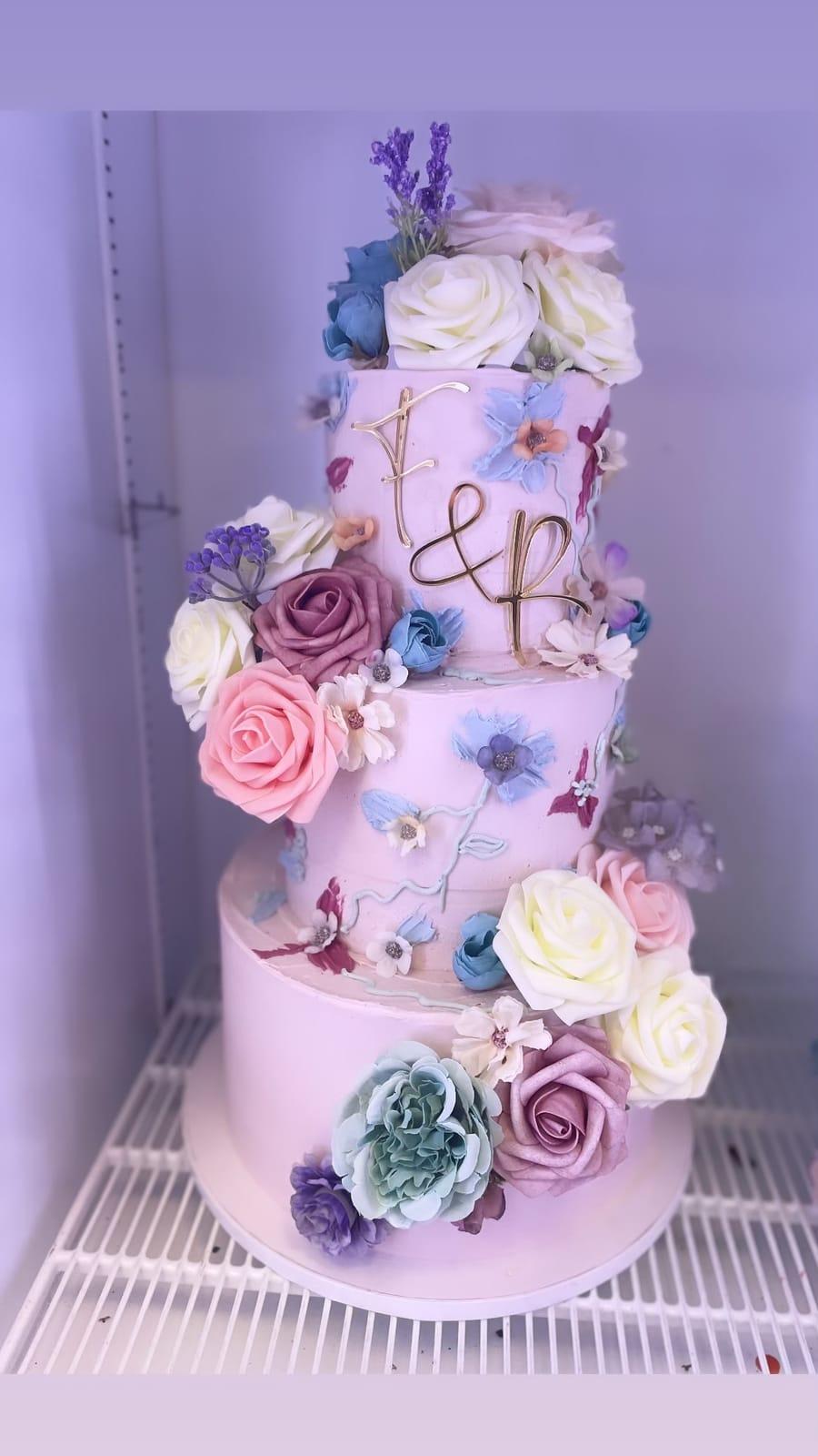 Bröllopstårta i tre våningar med rosa och lila rosor