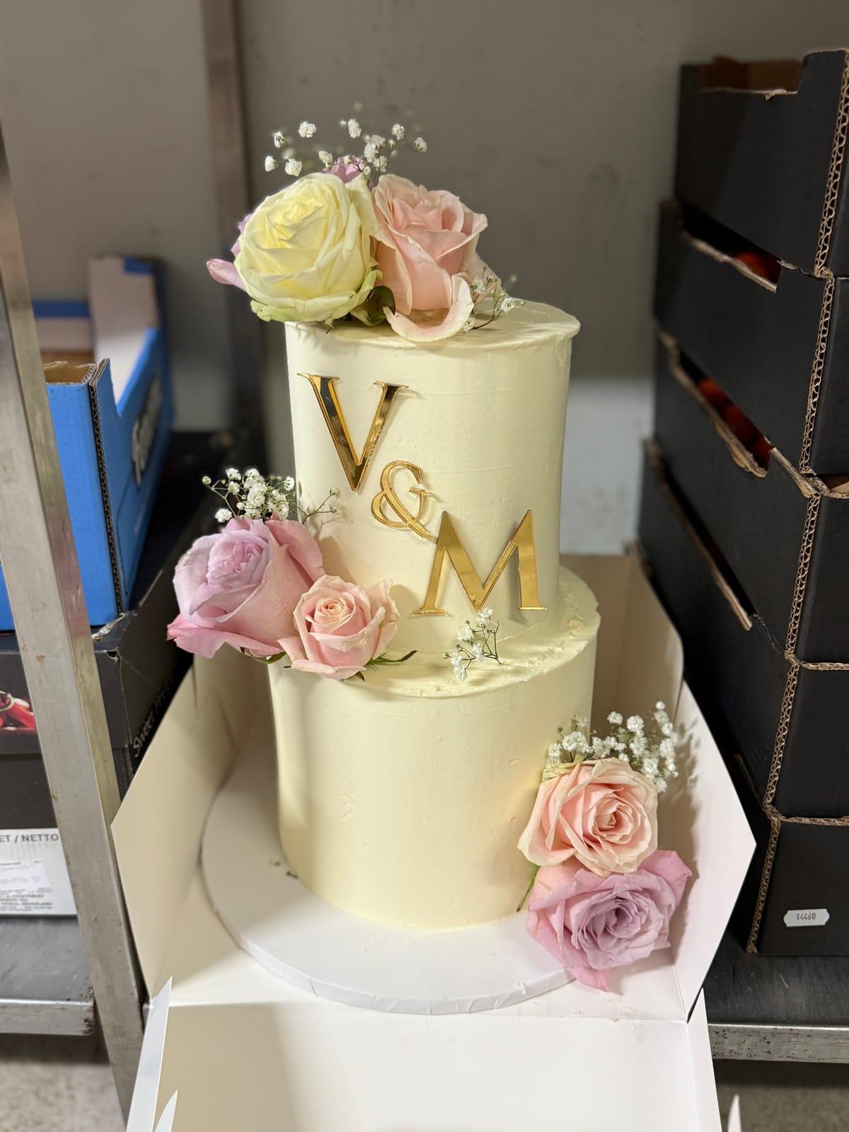 Bröllopstårta med rosa rosor och guldmonogram