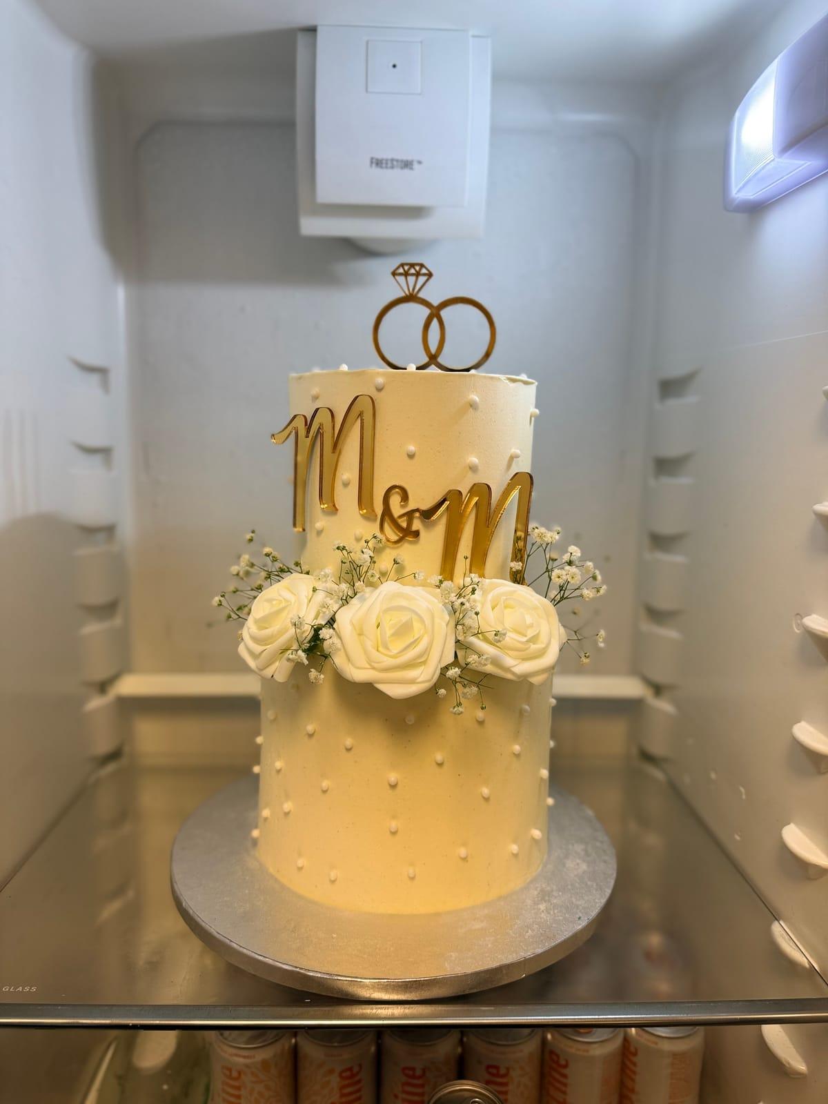 Förlovningstårta med ringtopper, vita rosor och guldmonogram